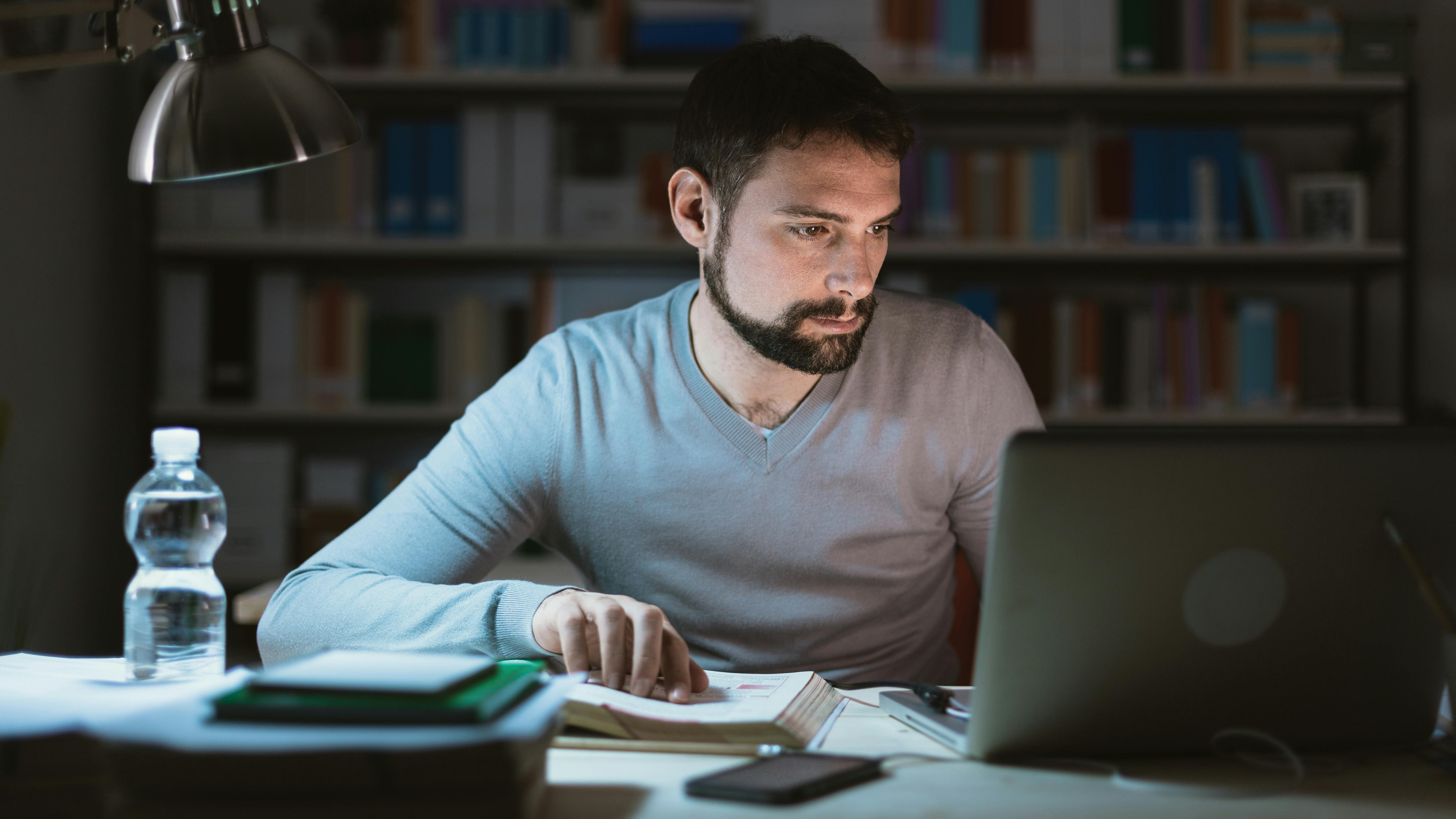 Un jeune homme fatigué travaille tard le soir à son bureau.